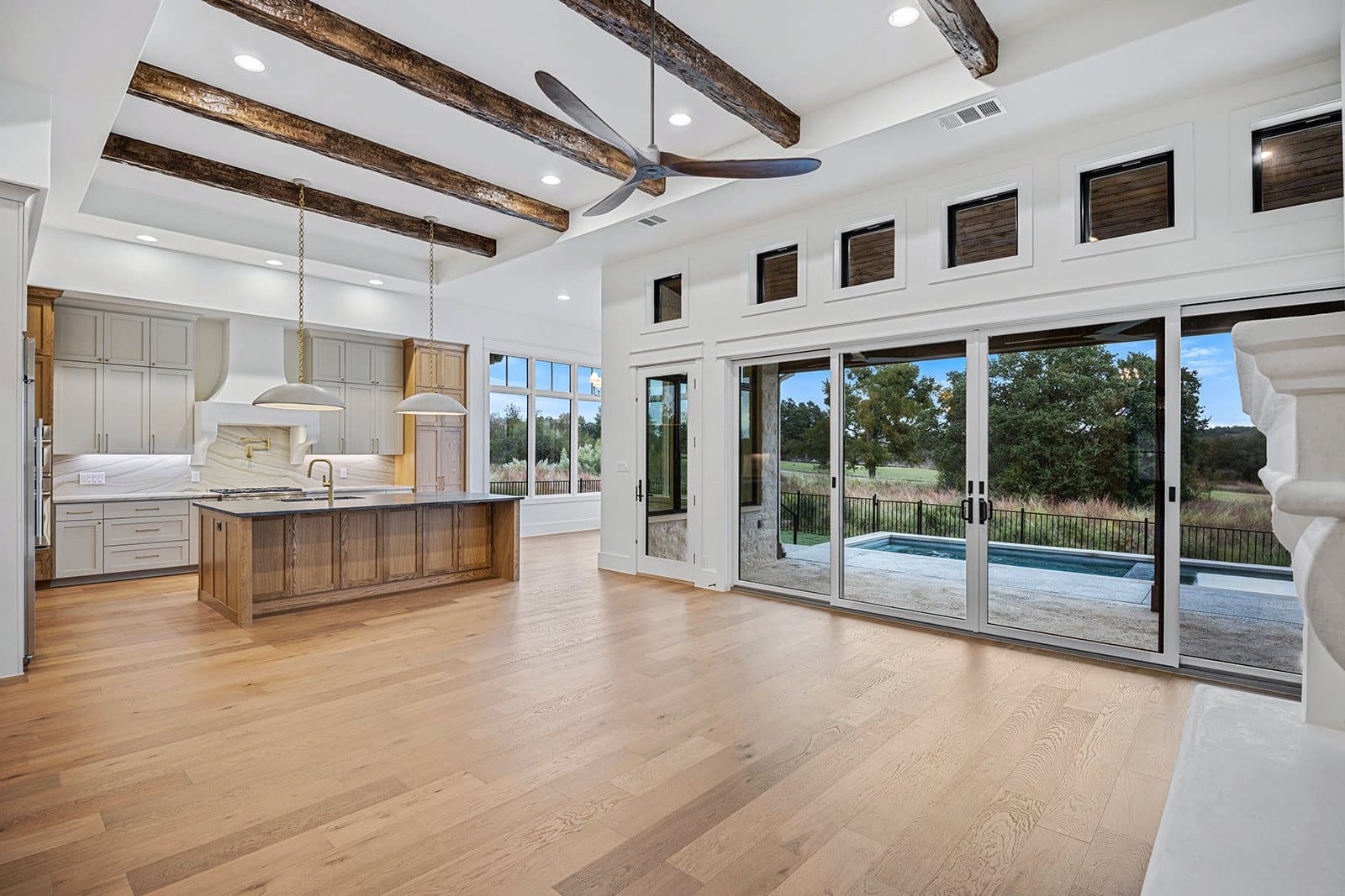Great room opening to the kitchen beneath exposed wood beams